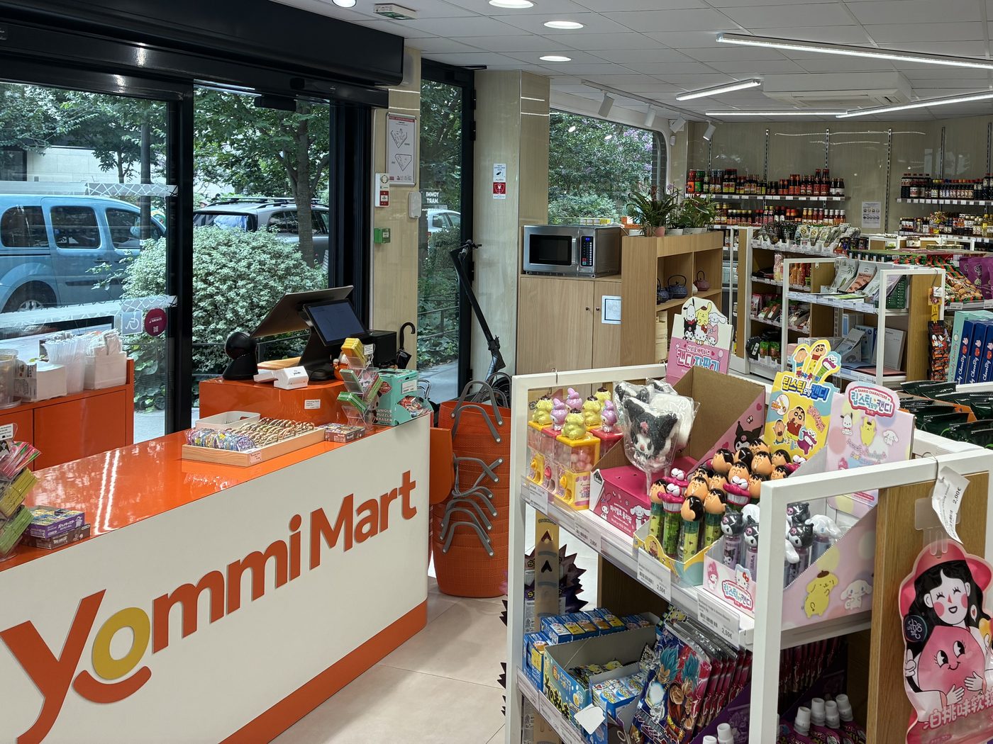 Intérieur lumineux de l'épicerie Yommi Mart : le comptoir Yommi Mart et les rayons de produits asiatiques